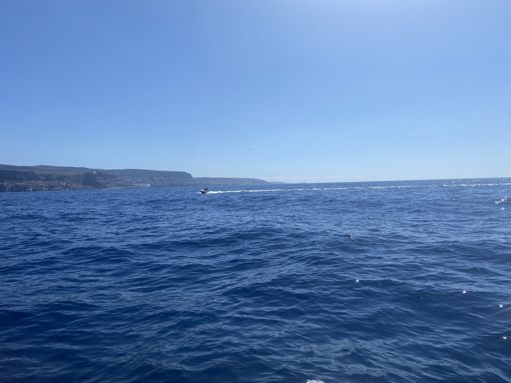 Jet ski and parasail in front of the coastline, viewed from a small boat from the jet ski to the Sagitarius Cat boat