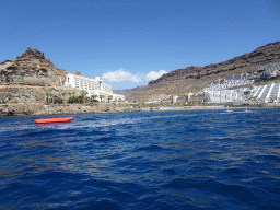 Banana boat and jet skis in front of the Playa del Diablito beach, viewed from the Sagitarius Cat boat