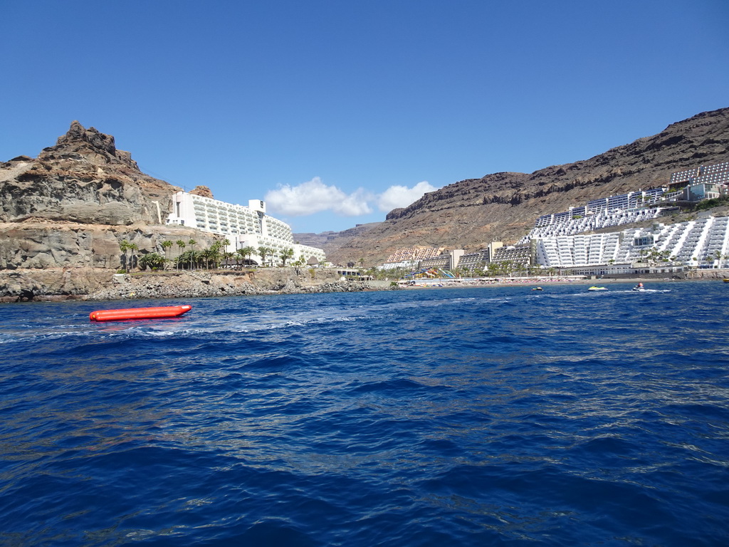 Banana boat and jet skis in front of the Playa del Diablito beach, viewed from the Sagitarius Cat boat