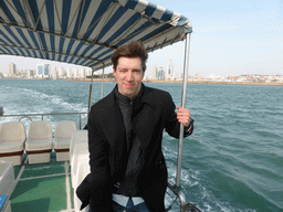 Tim on the tour boat, with a view on Qingdao Bay and skyscrapers at the city center