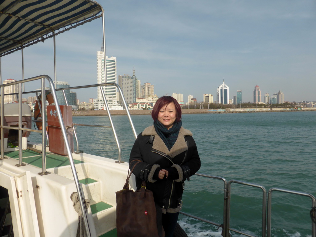 Miaomiao on the tour boat, with a view on Qingdao Bay and skyscrapers at the west side of the city and the city center