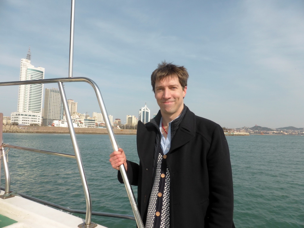 Tim on the tour boat, with a view on Qingdao Bay and skyscrapers at the west side of the city