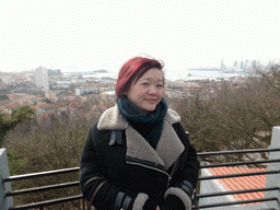 Miaomiao at the viewing point at the Xinhaoshan Park, with a view on the city center, Xiao Qingdao island and Zhan Qiao pier in Qingdao Bay and skyscrapers and dome at the west side of the city