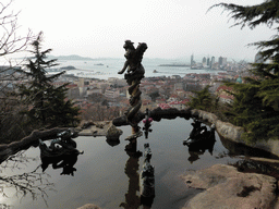 The Jade Dragon Pool at the Xinhaoshan Park, with a view on the city center, Xiao Qingdao island and Zhan Qiao pier in Qingdao Bay and skyscrapers and dome at the west side of the city