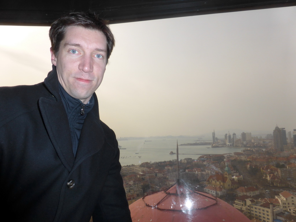 Tim at the rotating sightseeing tower at the Xinhaoshan Park, with a view on the city center with skyscrapers and the Qingdao Protestant Church, Qingdao Bay with the Zhan Qiao Pier and the skyscrapers and dome at the west side of the city