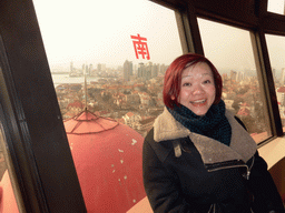 Miaomiao at the rotating sightseeing tower at the Xinhaoshan Park, with a view on the city center with skyscrapers, St. Michael`s Cathedral and the Qingdao Protestant Church, Qingdao Bay and the skyscrapers and dome at the west side of the city