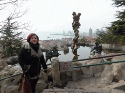 Miaomiao at the Jade Dragon Pool at the Xinhaoshan Park, with a view on the city center, Zhan Qiao pier in Qingdao Bay and skyscrapers and dome at the west side of the city