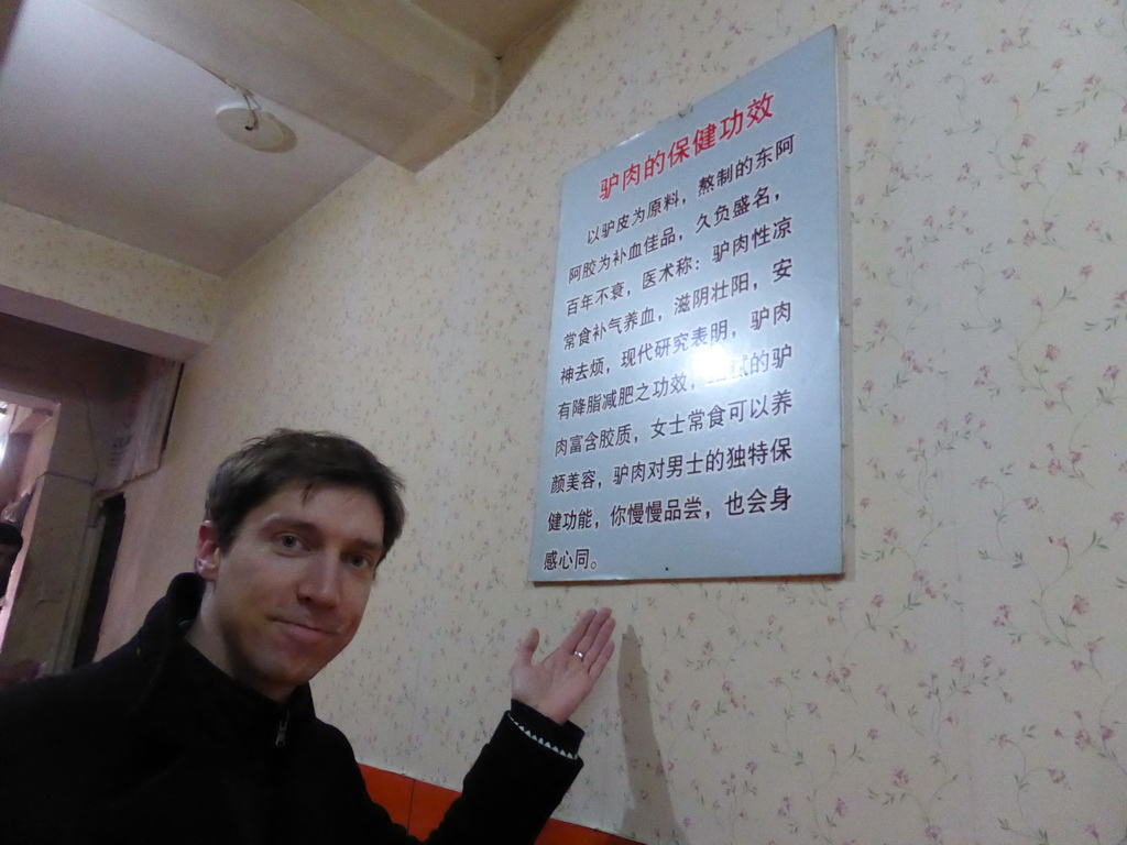 Tim with a sign in a donkey meat restaurant at Hubei Road