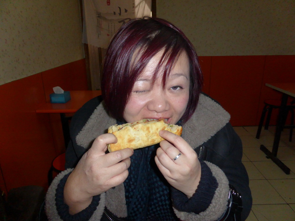 Miaomiao with a donkey meat sandwich in a donkey meat restaurant at Hubei Road