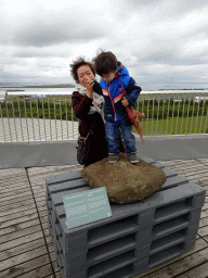 Miaomiao and Max on a sandstone rock with marine fossils on the roof of the Perlan building, with a view on Reykjavík Airport and surroundings