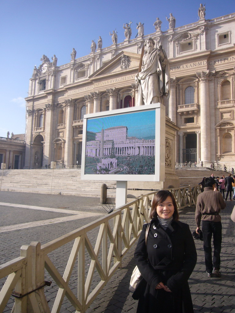 Miaomiao and the facade of St. Peter`s Basilica, with the Pope`s Window, the Statue of St. Paul and a big television screen