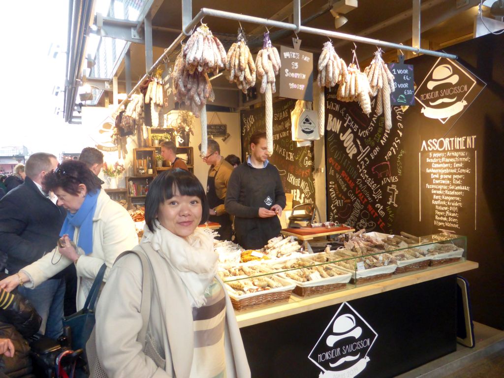 Miaomiao in front of a market stall with meat in the Markthal building
