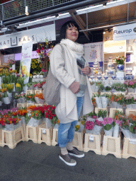 Miaomiao in front of a market stall with flowers in the Markthal building