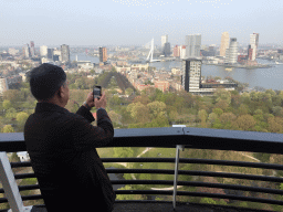 Miaomiao`s father at the upper viewing platform of the Euromast tower, with a view on the Park, the Westerlaantoren tower, the Erasmusbrug bridge over the Nieuwe Maas river and skyscrapers in the city center