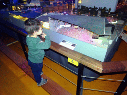 Max in front of a scale model of the Ahoy Rotterdam building at Miniworld Rotterdam, with explanation, in the dark