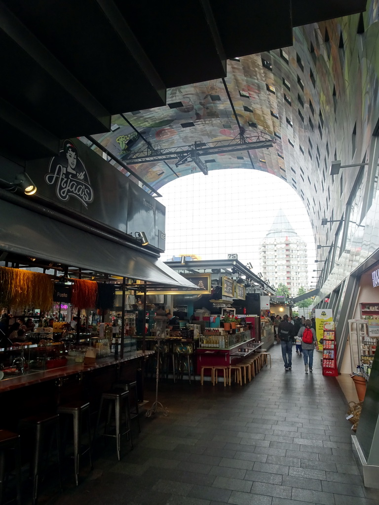 The Markthal building with its ceiling and market stalls, with a view on the Blaaktoren tower