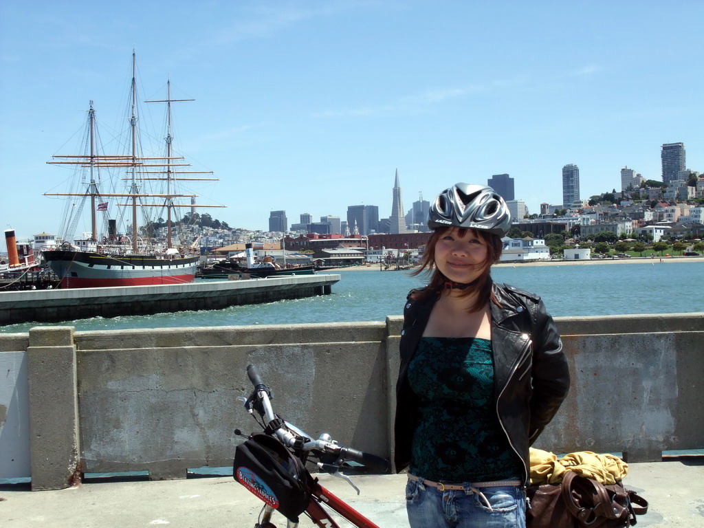 Miaomiao with bike, and boats in San Francisco Bay and the skyline of San Francisco, with the Transatlantic Pyramid