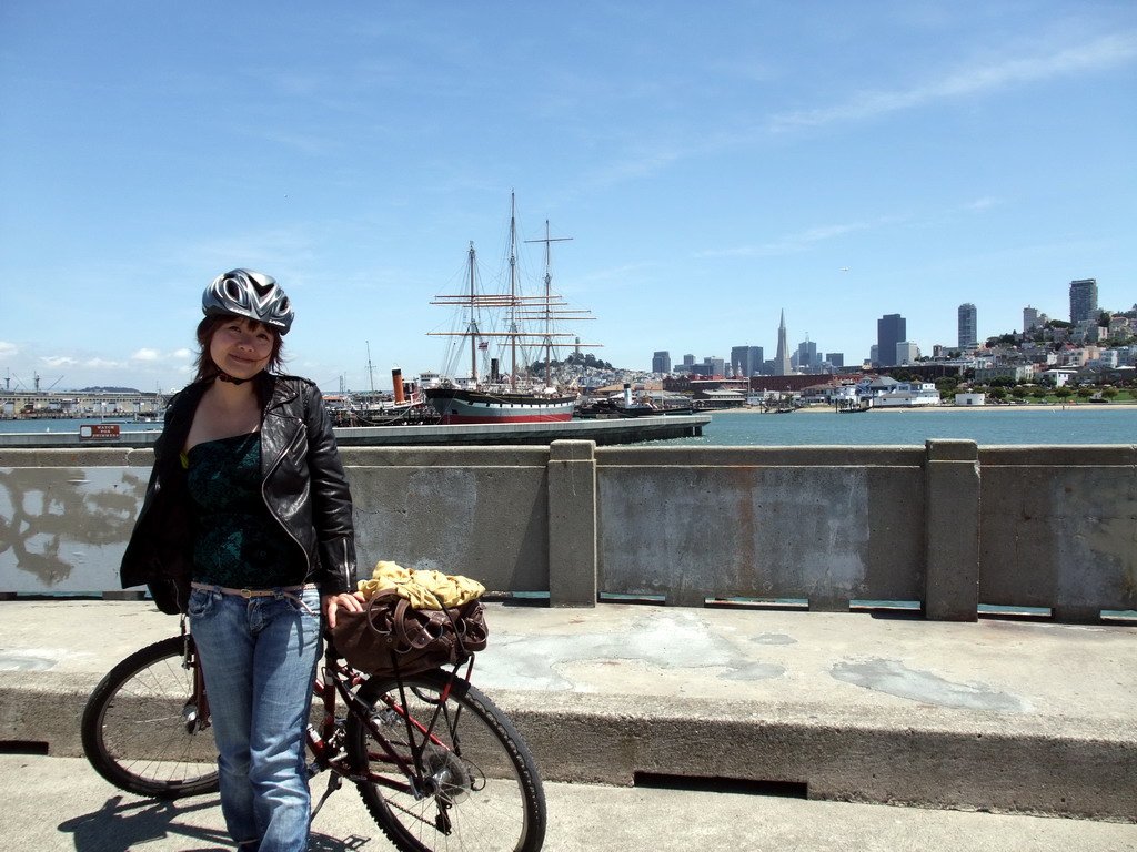 Miaomiao with bike, and boats in San Francisco Bay and the skyline of San Francisco, with the Transatlantic Pyramid