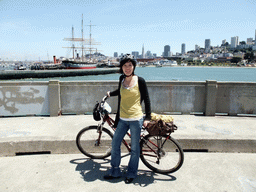 Mengjin with bike, and boats in San Francisco Bay and the skyline of San Francisco, with the Transatlantic Pyramid