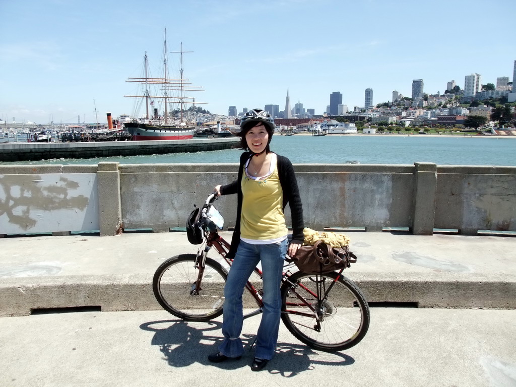 Mengjin with bike, and boats in San Francisco Bay and the skyline of San Francisco, with the Transatlantic Pyramid
