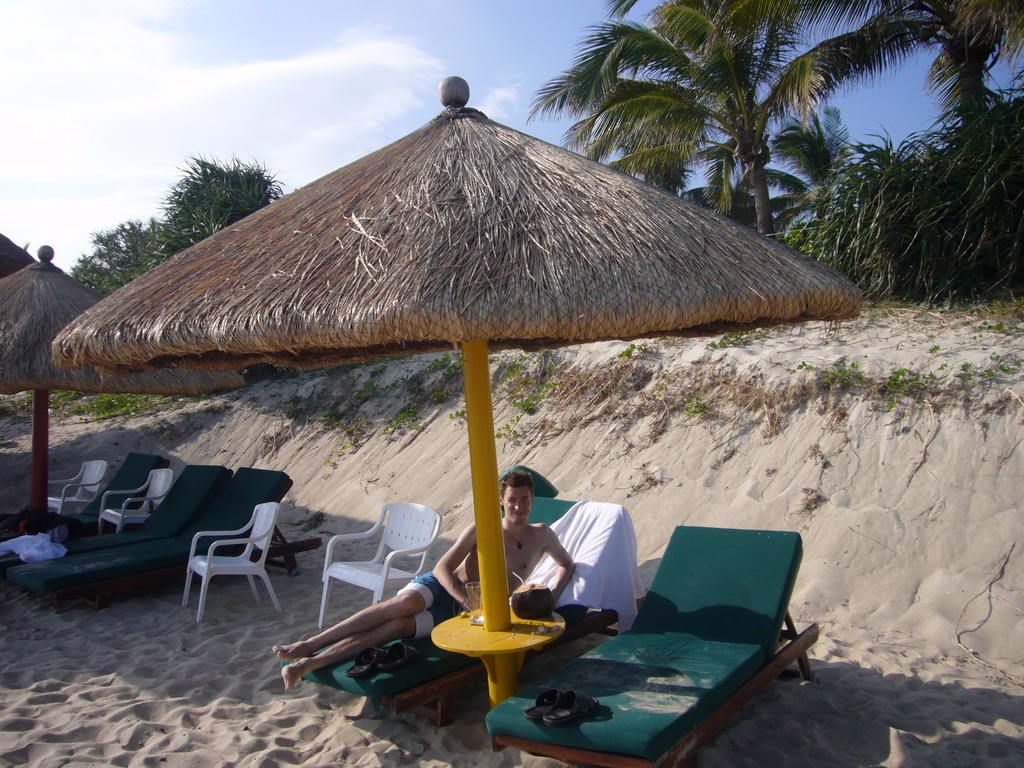 Tim in a lounge chair under an umbrella at the private beach of Gloria Resort Sanya