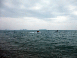 Jet skis and boats in the sea in front of the Ocean Sonic Resort, with a view on the skyline of Sanya