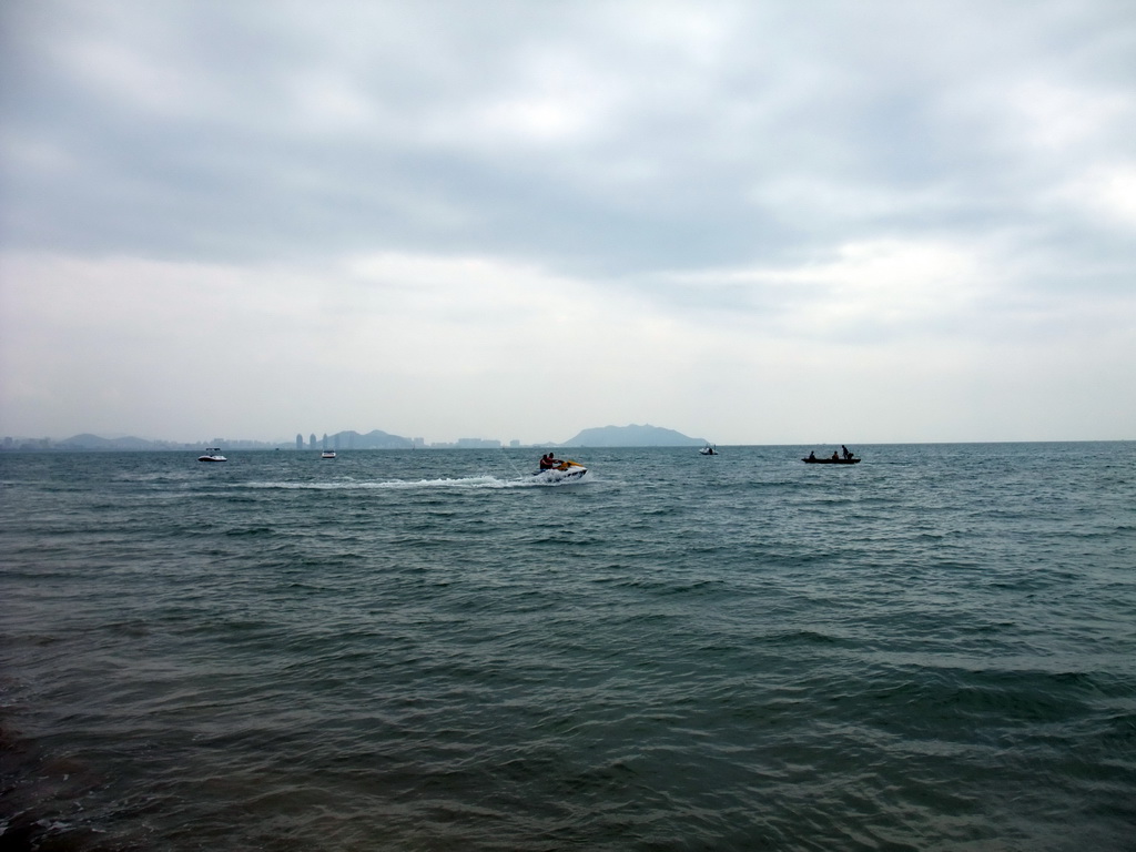 Jet skis and boats in the sea in front of the Ocean Sonic Resort, with a view on the skyline of Sanya