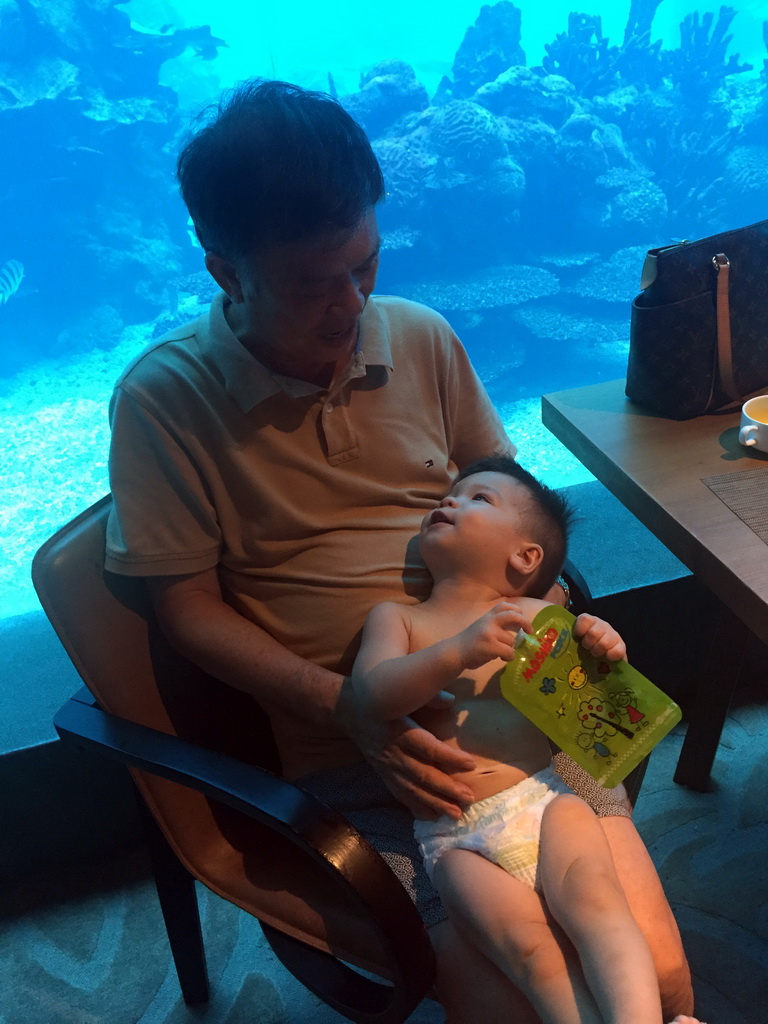 Max and Miaomiao`s father in front of the aquarium with fish at the Aqua restaurant at the InterContinental Sanya Haitang Bay Resort