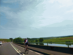 Cyclist and the Moselle river next to the Route du Vin road between Stadtbredimus and Hettermillen, viewed from the car