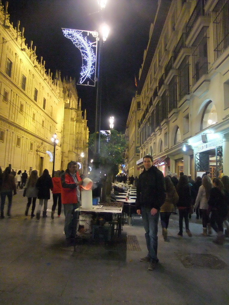 Tim with chestnut salesman in the Avenida de la Constitución avenue at the west side of the Seville Cathedral, by night