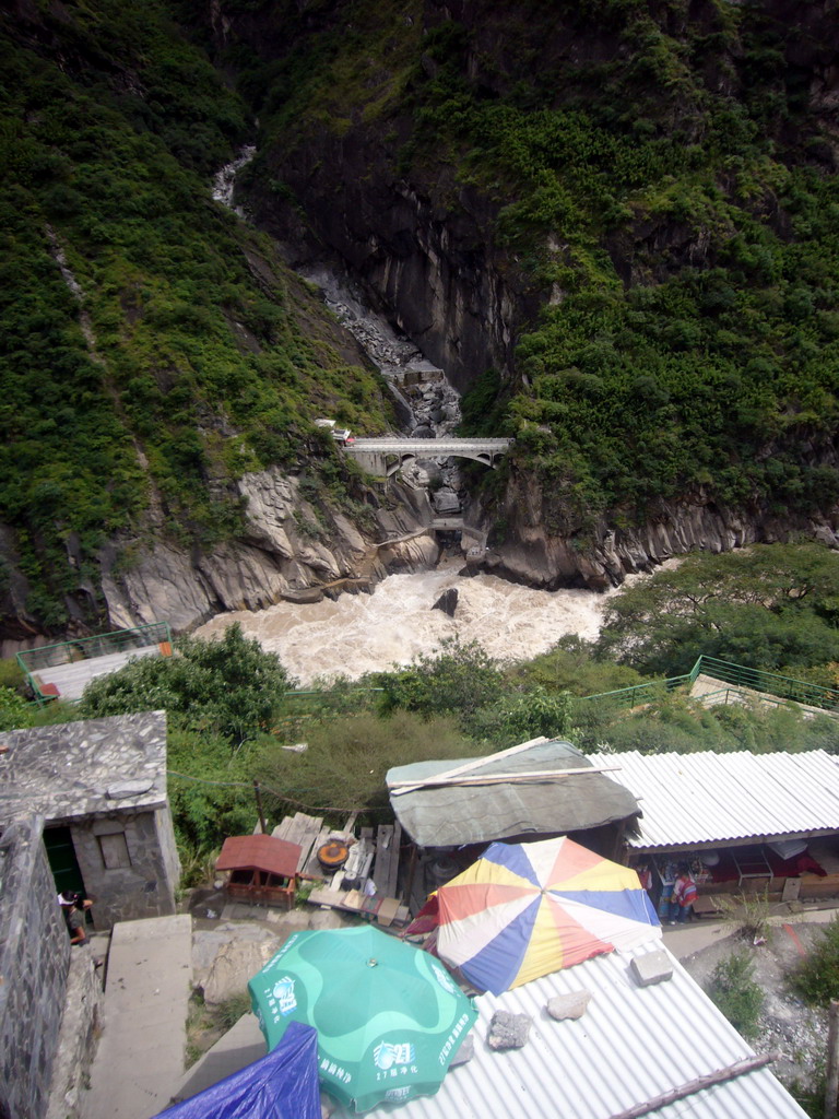 Bridge and track with small shops alongside at Tiger Leaping Gorge, viewed from the parking place