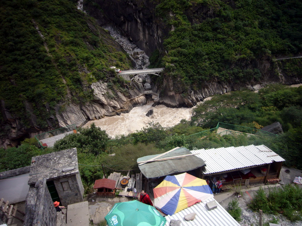 Bridge and track with small shops alongside at Tiger Leaping Gorge, viewed from the parking place