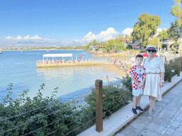 Miaomiao and Max at the seaside path near the Turgut Reis Caddesi street, with a view on boats in the Gulf of Antalya and beaches, hotels and a mosque at the northwest side of town