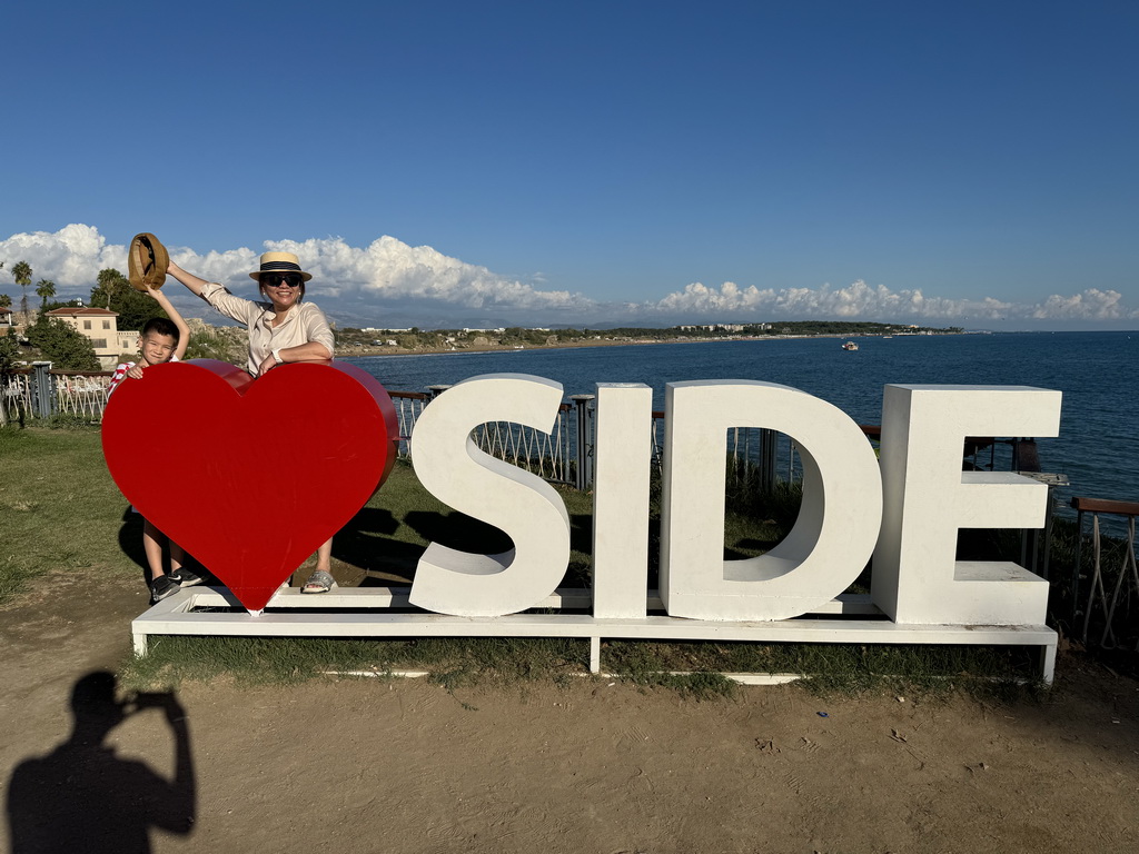 Miaomiao and Max with a Love Side sign at the Barbaros Caddesi street, with a view on beaches and hotels at the northeast side of town