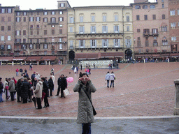 Miaomiao`s friend in front of the Gaia Fountain and the Loggia della Mercanzia building at the Piazza del Campo square