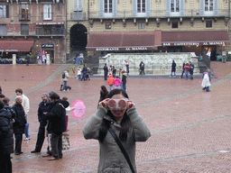 Miaomiao`s friend in front of the Gaia Fountain and the Loggia della Mercanzia building at the Piazza del Campo square