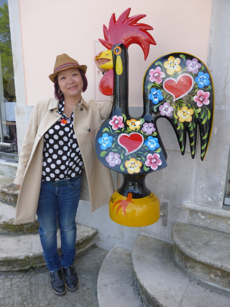 Miaomiao with a painted rooster statue at the Rua Visconde Monserrate street