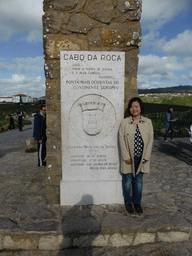 Miaomiao at the plaque with inscription `Westernmost Point of Continental Europe` at the column with cross at the Cabo da Roca cape