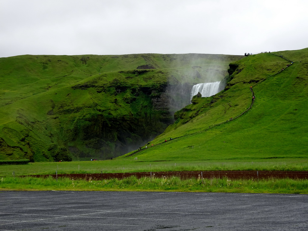 The Skógafoss waterfall with the trail and platform on the east side, viewed from the parking lot of the Fossbúð restaurant