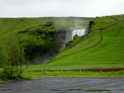 The Skógafoss waterfall with the trail and platform on the east side, viewed from the parking lot of the Fossbúð restaurant