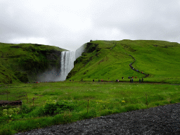 The Skógafoss waterfall with the trail and platform on the east side, viewed from the parking lot