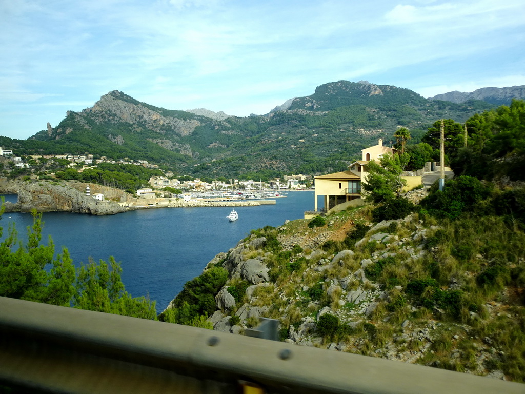 Boats in the harbour and the Faro de Punta de Sa Creu lighthouse, viewed from the rental car on the Camí del Far street