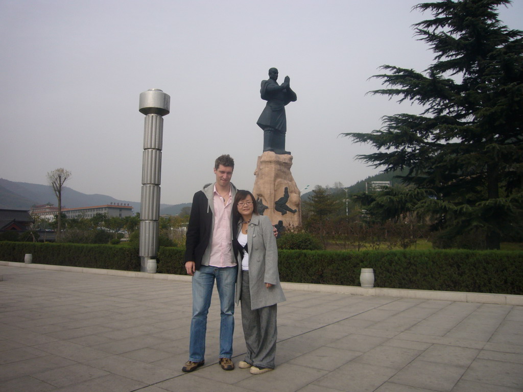 Tim and Miaomiao with statue at entrance of Shaolin Monastery