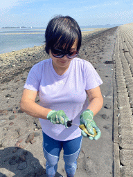 Miaomiao opening an oyster at the beach near the Dijkweg road