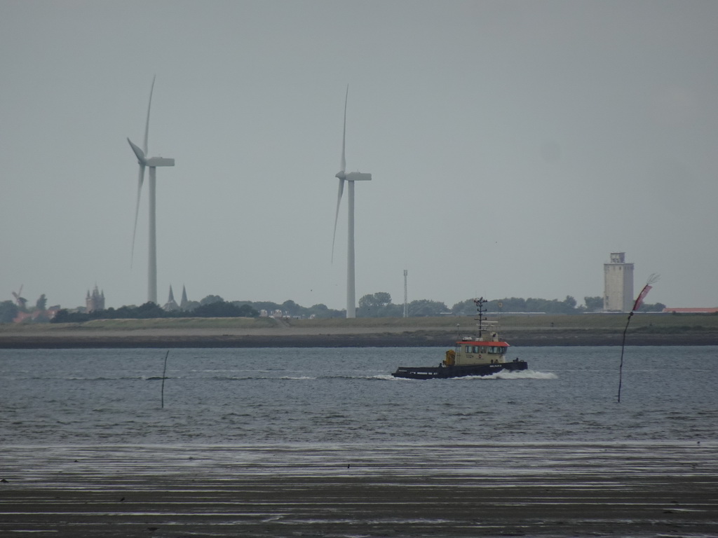 Boat on the National Park Oosterschelde, windmills and the city center of Zierikzee, viewed from the beach near the Dijkweg road