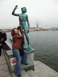 Miaomiao with the bronze sculpture `Sangen` in the garden of the Stockholm City Hall, with a view on Riddarfjärden bay and Riddarholmen island