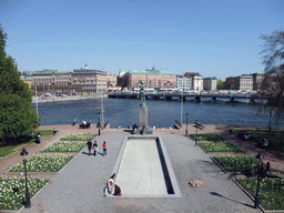 Park with statue in front of the Museum of Medieval Stockholm (Stockholms medeltidsmuseum), and the Strömbron bridge over the Norrström river