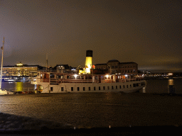 Boat in the Stockholms Ström river, viewed from the Skeppsbron street, by night