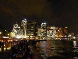 The Lower Concourse of the Sydney Opera House, with a view on the Sydney Cove, the Circular Quay Wharf, the Circular Quay Railway Station and skyscrapers at the city center, by night