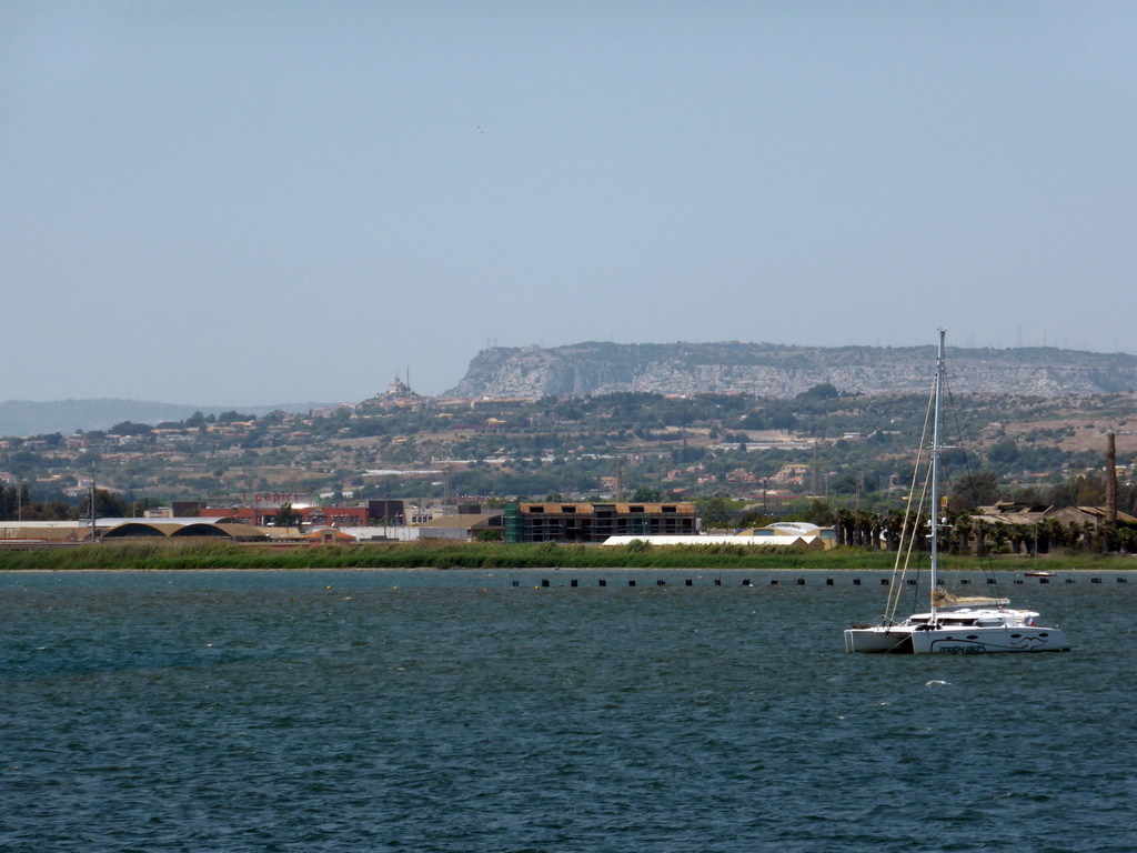 Boat in the Porto Grande harbour and buildings and hills on the other side of the Porte Grande harbour, viewed from the Lungomare Alfeo street